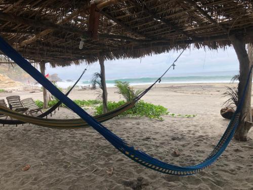 a blue hammock hanging from a hut on a beach at Hab #5 La Casa Del Profe Salo in Santa María Tonameca