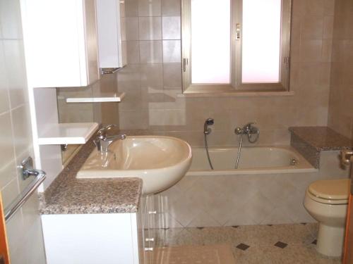 een badkamer met een wastafel, een bad en een toilet bij Villetta con giardino a 5 minuti dal mare in Flumini di Quartu
