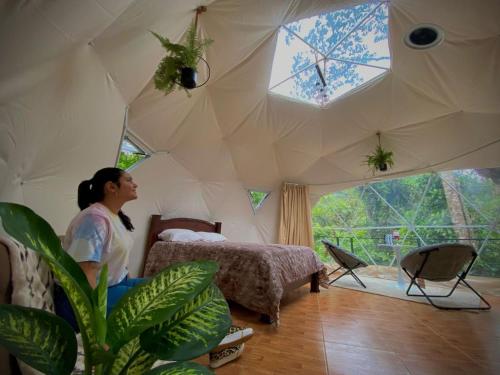 a woman sitting in a room with a bed in a tent at Hotel Rivel - Restaurant & Nature Retreat in Turrialba