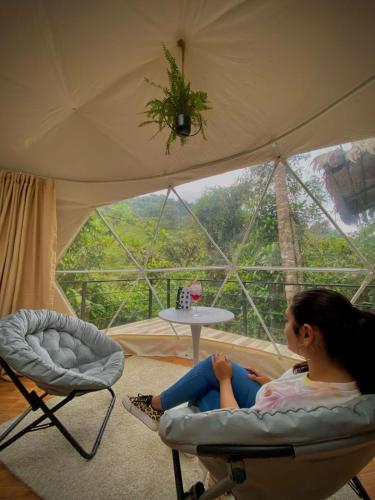 a woman sitting in a chair in a tent at Hotel Rivel - Restaurant & Nature Retreat in Turrialba