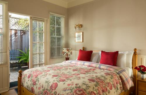 a bedroom with a bed with red pillows at Cheshire Cat Inn & Cottages in Santa Barbara