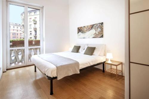 Un dormitorio blanco con una cama y una ventana grande. en [Buenos Aires Residence] - Stazione Centrale, en Milán