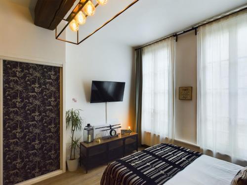 een slaapkamer met een bed en een tv aan de muur bij Studio Deschainets Troyes Gare et Centre Historique in Troyes