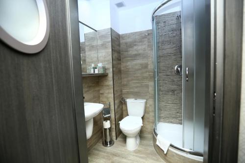 uma casa de banho com um WC e uma cabina de duche em vidro. em Hotel Forma em Pila