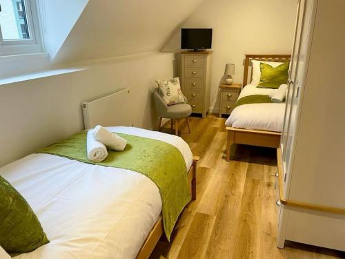 a small bedroom with two beds and a chair at The Old Barn Apartment in Wells next the Sea