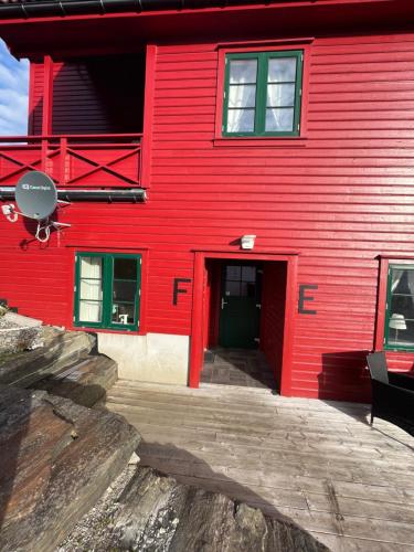 a red building with a red door in front of it at Sjøberg Hotell og Ferie Leiligheter in Østhusvik