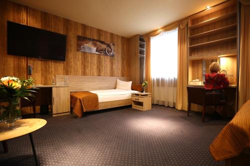 pokój hotelowy z łóżkiem i osobą siedzącą na krześle w obiekcie Hotel Forma w mieście Piła