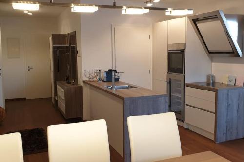 eine Küche mit einer Theke und weißen Stühlen in der Unterkunft Wohnung am Wörthersee in Velden am Wörthersee