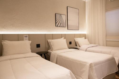 two beds in a room with white sheets at Morada Inn Hotel in Franca