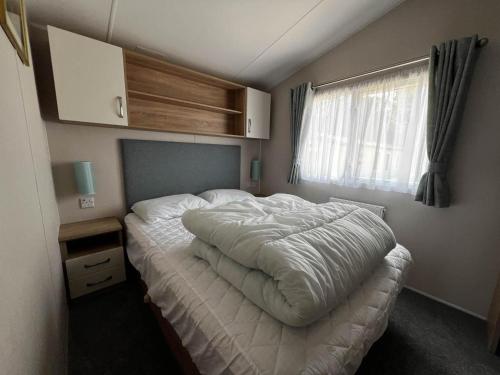 una camera da letto con un grande letto bianco e una finestra di 6 Berth Caravan With Stunning Sea Views And Decking To Relax On, Ref 32048az a Lowestoft