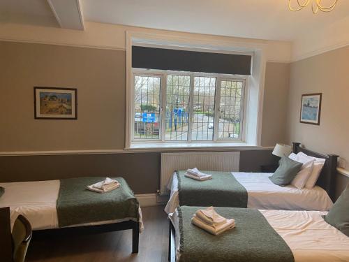 ein Hotelzimmer mit zwei Betten und einem Fenster in der Unterkunft The Swan Inn Pub in Isleworth