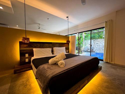 a bedroom with a large bed with a large window at Kuun Taak Tulum in Tulum