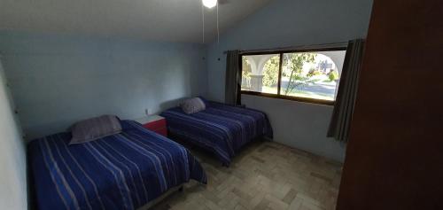 2 letti in una piccola camera con finestra di Casa en lomas de Cocoyoc a Texcalpan