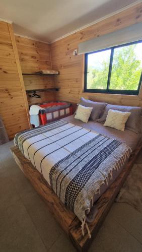 a large bed in a room with wooden walls at Peumayenlodge in Antuco