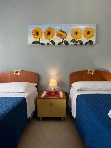 a room with two beds and a picture of sunflowers on the wall at Coccinella B&B a Tufo in Tufo