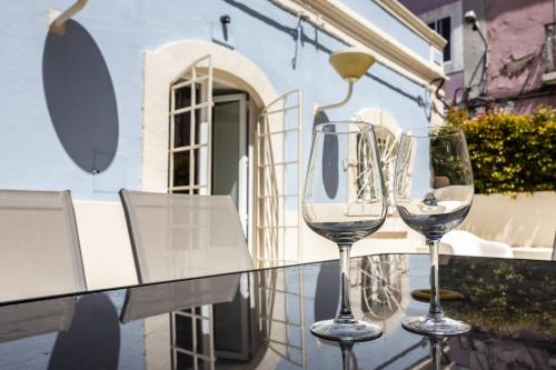 three wine glasses sitting on a glass table on a balcony at Postigo do Cais - By Y Concept in Setúbal