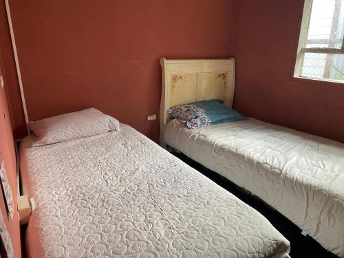 2 camas en una habitación pequeña con paredes rojas en La cabaña en Chaitén