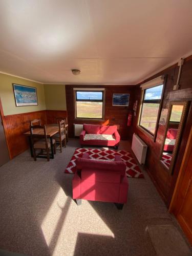 salon z czerwoną kanapą i stołem w obiekcie Cabañas Lago Tyndall w mieście Torres del Paine