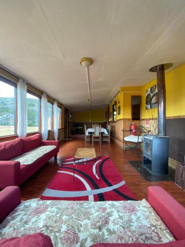 a living room with a red couch and a rug at Cabañas Lago Tyndall in Torres del Paine