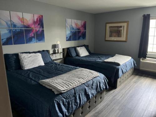 een slaapkamer met 2 bedden en schilderijen aan de muur bij Gamble Farm Inn and Suites 