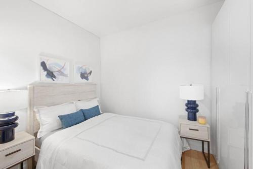 um quarto com uma cama branca e duas mesas de cabeceira em 69-2C Brand New PRIME Lower East Side 1br Apt em Nova York