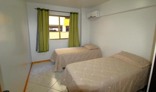 1 dormitorio con 2 camas y ventana en 1029 - Apartamento no centro de Bombinhas - Residencial estrela do mar 2 104 A, en Bombinhas