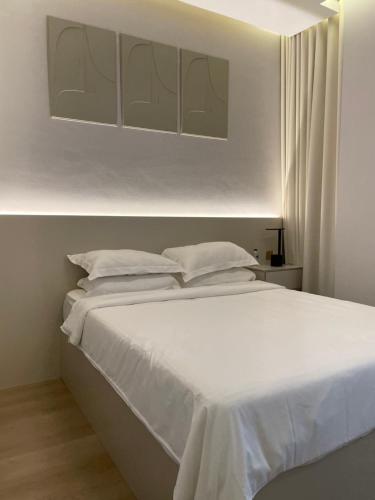 Cama blanca con sábanas y almohadas blancas en 1 BR Luxury Apt by AJ Aljada, en Sharjah