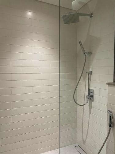 a shower with a glass door and a shower head at 1 BR Luxury Apt by AJ Aljada in Sharjah