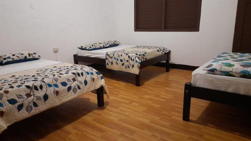 three beds in a room with wooden floors at Hotel Sansívar in León