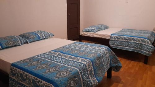 a room with three beds with blue and white covers at Hotel Sansívar in León