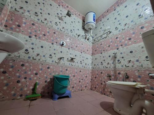 a bathroom with a pink tiled wall with a toilet at Shanti guest house chojh in Kasol