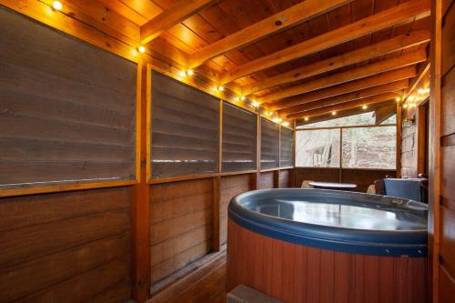 a jacuzzi tub in a room with wooden walls at 5 Mins to Pigeon Forge Strip w/ Hot Tub+Grill+MORE in Pigeon Forge