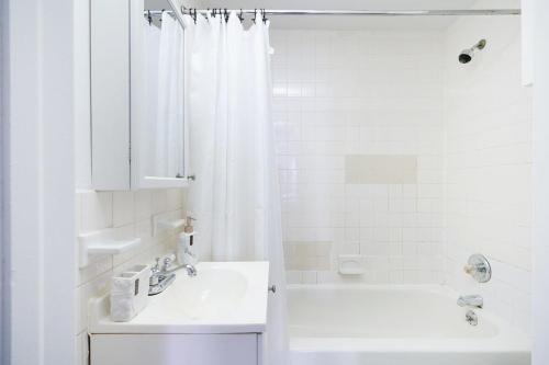 a white bathroom with a sink and a shower at 83-2FE UES Central Park Newly Furnished Studio in New York