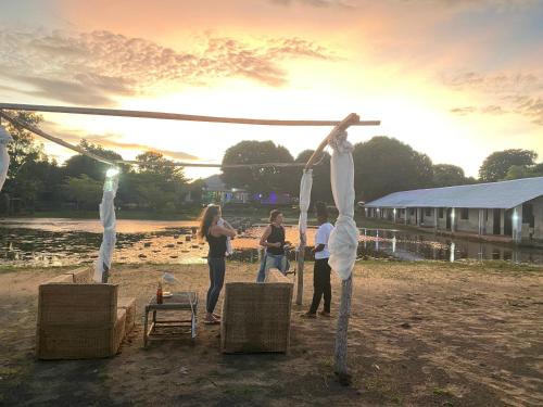 a group of people standing around a wooden pole at Main Stream Beach Villa in Senga