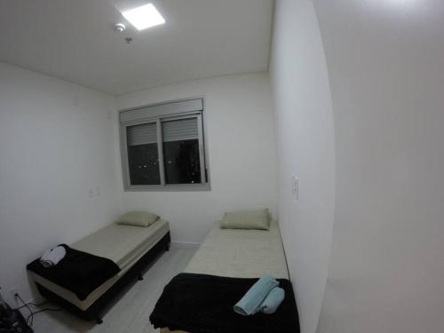 2 Betten in einem weißen Zimmer mit Fenster in der Unterkunft Apartamento inteiro aconchegante, ótima localização! in Osasco