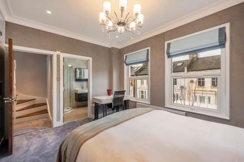 sypialnia z łóżkiem, biurkiem i oknami w obiekcie Luxury Apartments Victoria, London Eye, Big Ben w Londynie