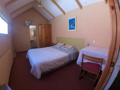 1 dormitorio pequeño con 2 camas y 1 silla en Hotel Sol de Alicante en Los Ángeles
