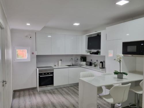 a kitchen with white cabinets and a table and chairs at Mikaela Guest House in Odivelas
