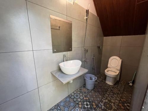 a bathroom with a sink and a toilet at Wetlands Wayanad Pool Resort with Natural Waterfalls in Padinjarathara