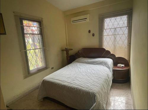 a bedroom with a bed and two windows at Casa en San Cristóbal, urb los naranjos in San Cristóbal