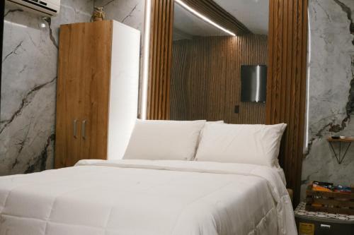 1 dormitorio con cama blanca y armario de madera en Búho Kite Hotel Boutique, en Salina de Rey