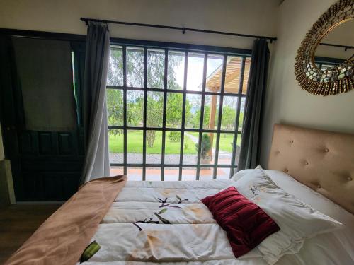 a bedroom with a bed and a large window at Quinta Paolita in Tumbabiro