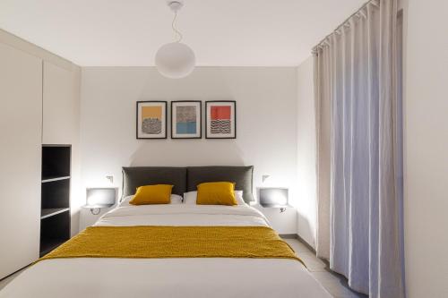 um quarto com uma cama grande e 2 almofadas amarelas em MarAvilia Apartment, vicino al Monte Tamaro e al parco acquatico Splash & SPA em Monte Ceneri