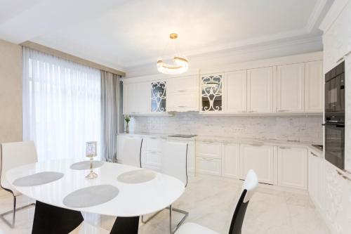 - une cuisine blanche avec une table et des chaises blanches dans l'établissement 2BD-2BATH Apartment in Tbilisi City Centre, à Tbilissi