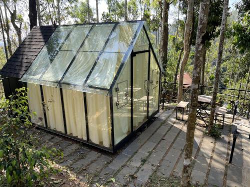 een glazen huis met een bank op een terras bij Wetlands Wayanad Resort with Natural Waterfalls in Padinjarathara