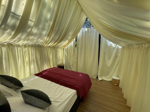 a bedroom with white curtains and a bed with pillows at Wetlands Wayanad Pool Resort with Natural Waterfalls in Padinjarathara