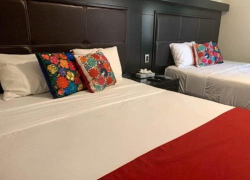 a hotel room with two beds with colorful pillows at Hacienda Santa Ireme in Zapotlanejo