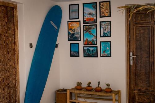 a blue surfboard hanging on a wall with pictures at Soul Surf House Anza in Agadir