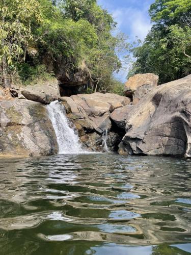 a waterfall next to a pool of water at Wetlands Wayanad Pool Resort with Natural Waterfalls in Padinjarathara