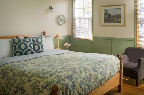 a bedroom with a bed and a chair at Cheshire Cat Inn & Cottages in Santa Barbara